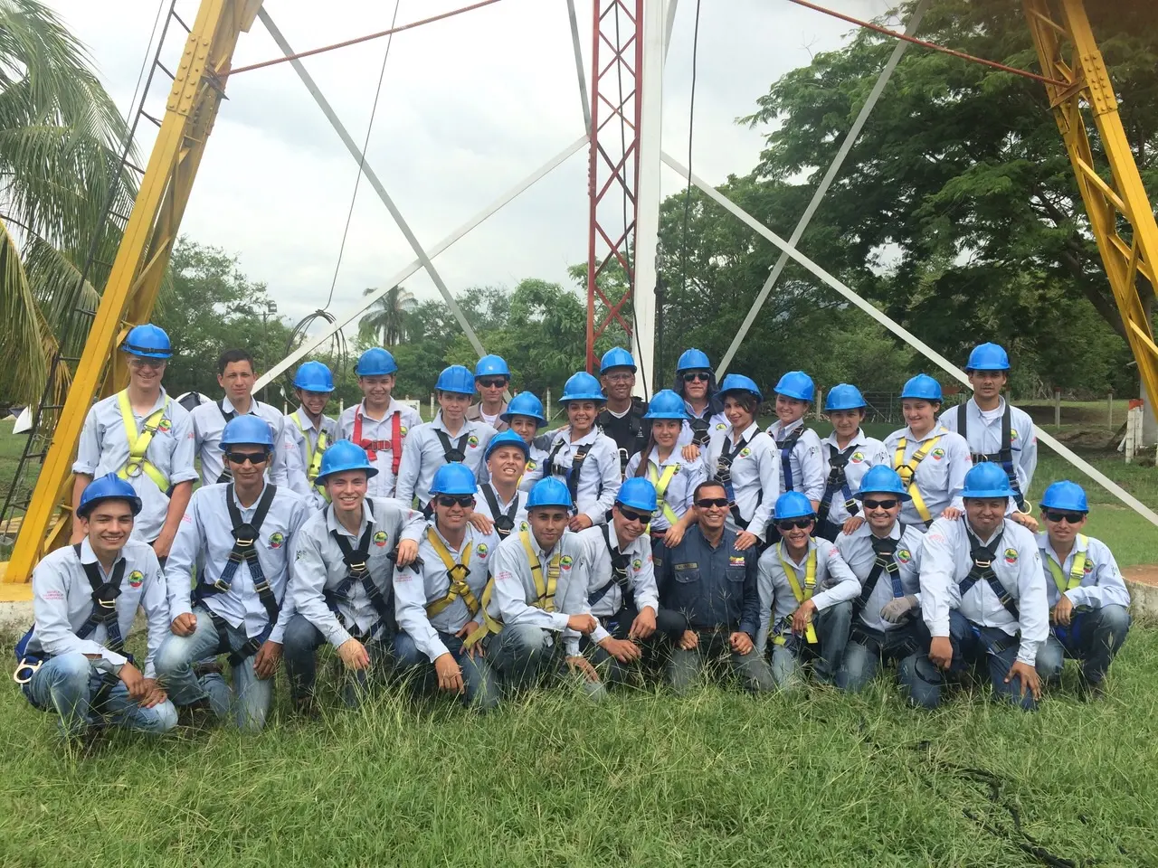 Grupo de estudiantes con casco y arnés frente a la torre de entrenamiento