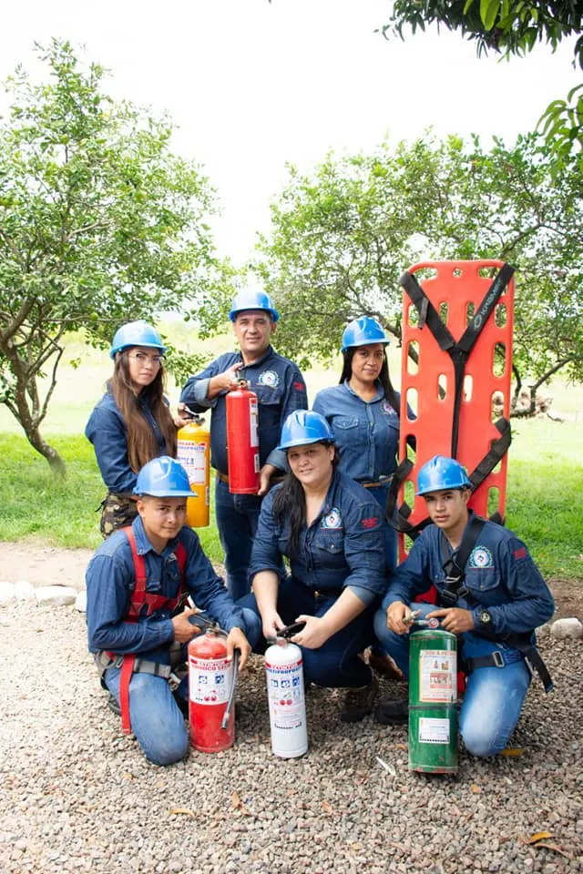 Estudiantes con uniforme y casco posan con extintores y una camilla de rescate